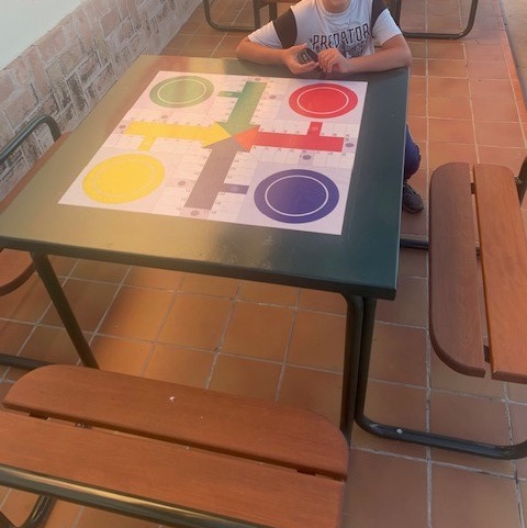 niño jugando en mesa urbana de parchis